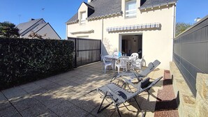 A house with a patio, a dining area with chairs and a table, and a covered outdoor seating area.