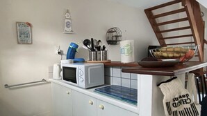 A kitchen with a microwave, a sink, and a trash bin.