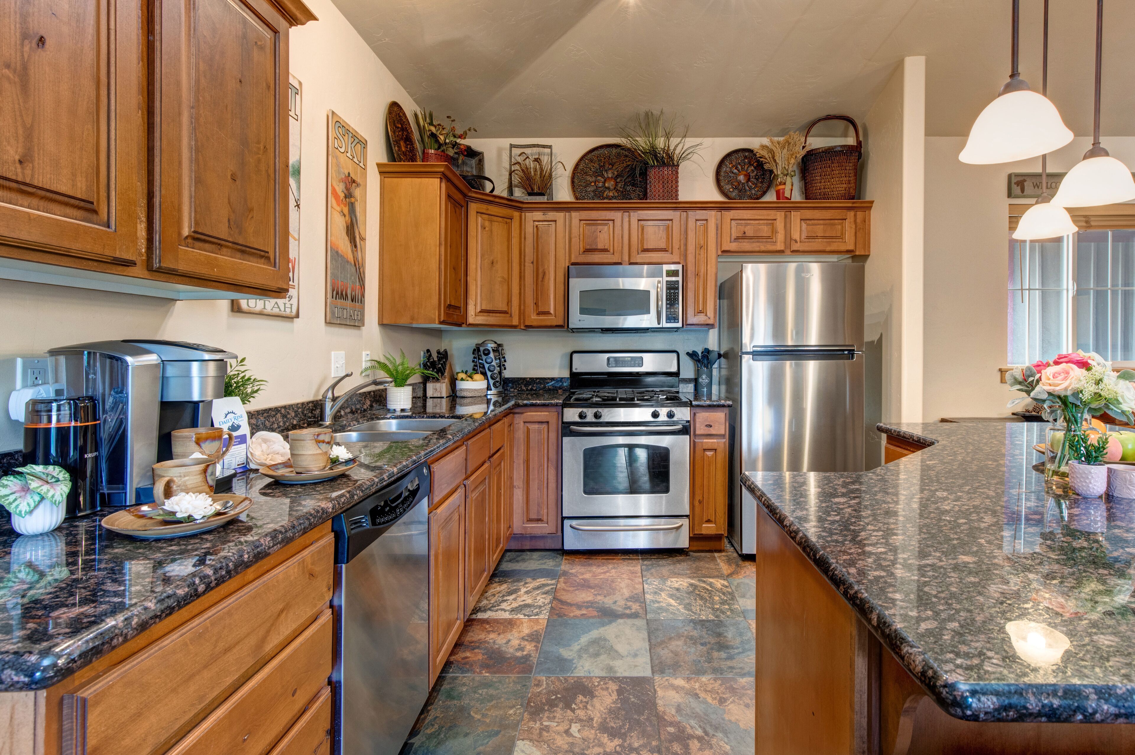 A kitchen with wooden cabinets, stainless steel appliances, granite countertops, and decorative items.