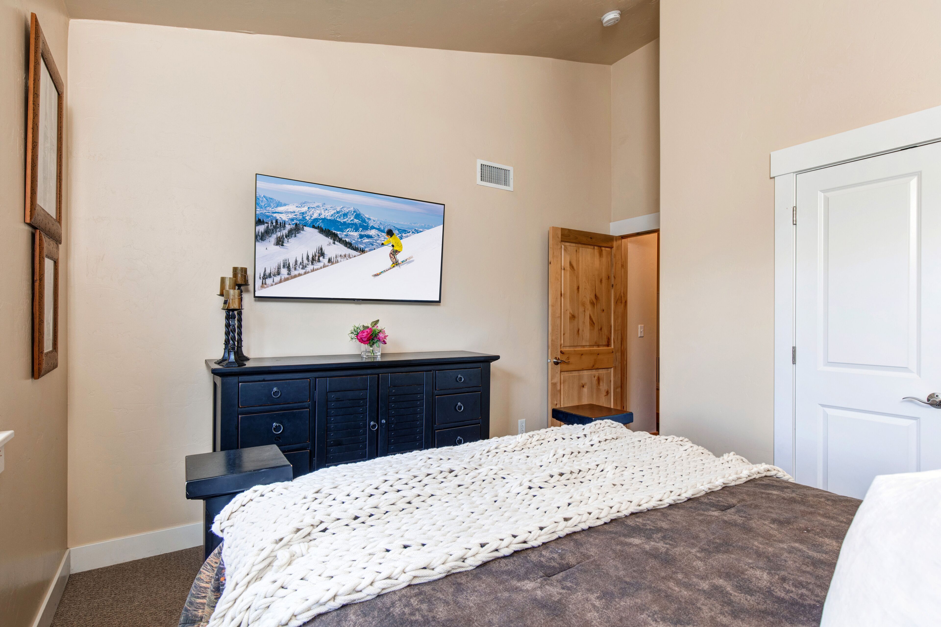 Ein Schlafzimmer mit einem Bett, einer Kommode, einem Bild eines Skifahrers und einer Tür.