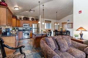 A spacious living area with a large sofa, a kitchen with modern appliances, and a dining area with a table and chairs. - Enjoy Luxury Community Amenities, Pet-friendly & Free Shuttle- Near Utah Olympic Park! (Park City)