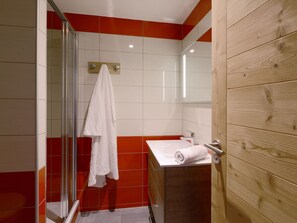 A bathroom with a glass shower enclosure, a wooden vanity, and a red and white tiled wall. - Renovated Studio 2 pers · Wellness · Pets allowed (La Plagne Montchavin Les Coches)
