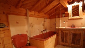 Un baño de cabaña de madera con inodoro, bañera de madera y lavamanos.