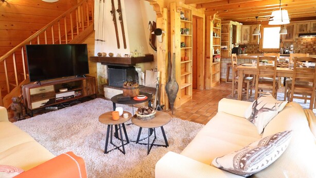 Acogedor interior de cabaña de madera con chimenea, muebles de madera y comedor.