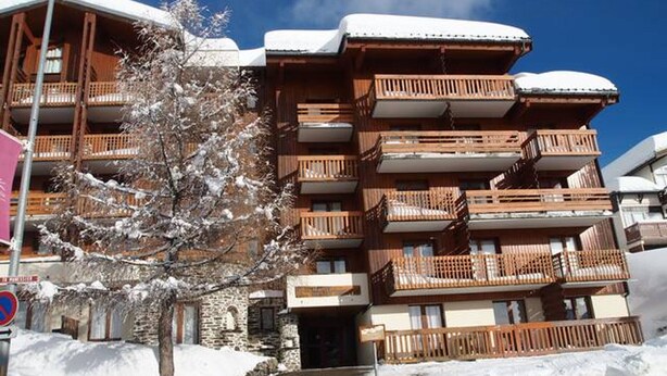 Un hotel a più piani con balconi in legno e tetti imbiancati dalla neve.