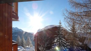 Paesaggio montano innevato con un edificio e alberi.