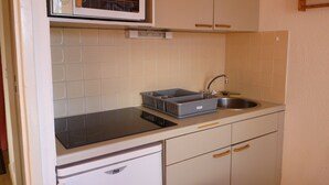 Una cucina compatta con forno a microonde, lavandino e scolapiatti.