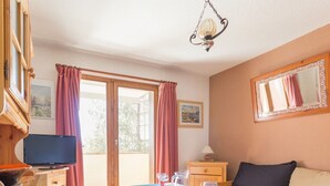 Una stanza con un letto, un tavolo apparecchiato per mangiare, una televisione e una finestra con tende.
