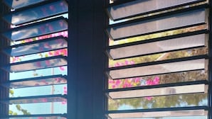 A window with horizontal blinds, allowing a view of outdoor scenery including flowers and a pool. - - Gli Orizzonti di Agata - Villa with a wide view of the sea - MARGHERITA - (Puglia)