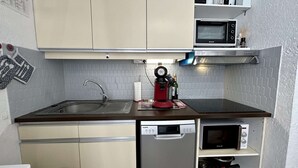 Een kleine keuken met een spoelbak, een rode koffieapparaat, een magnetron en een vaatwasser.