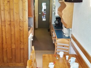 A wooden interior with a dining table, chairs, and a kitchen area with a coffee maker.