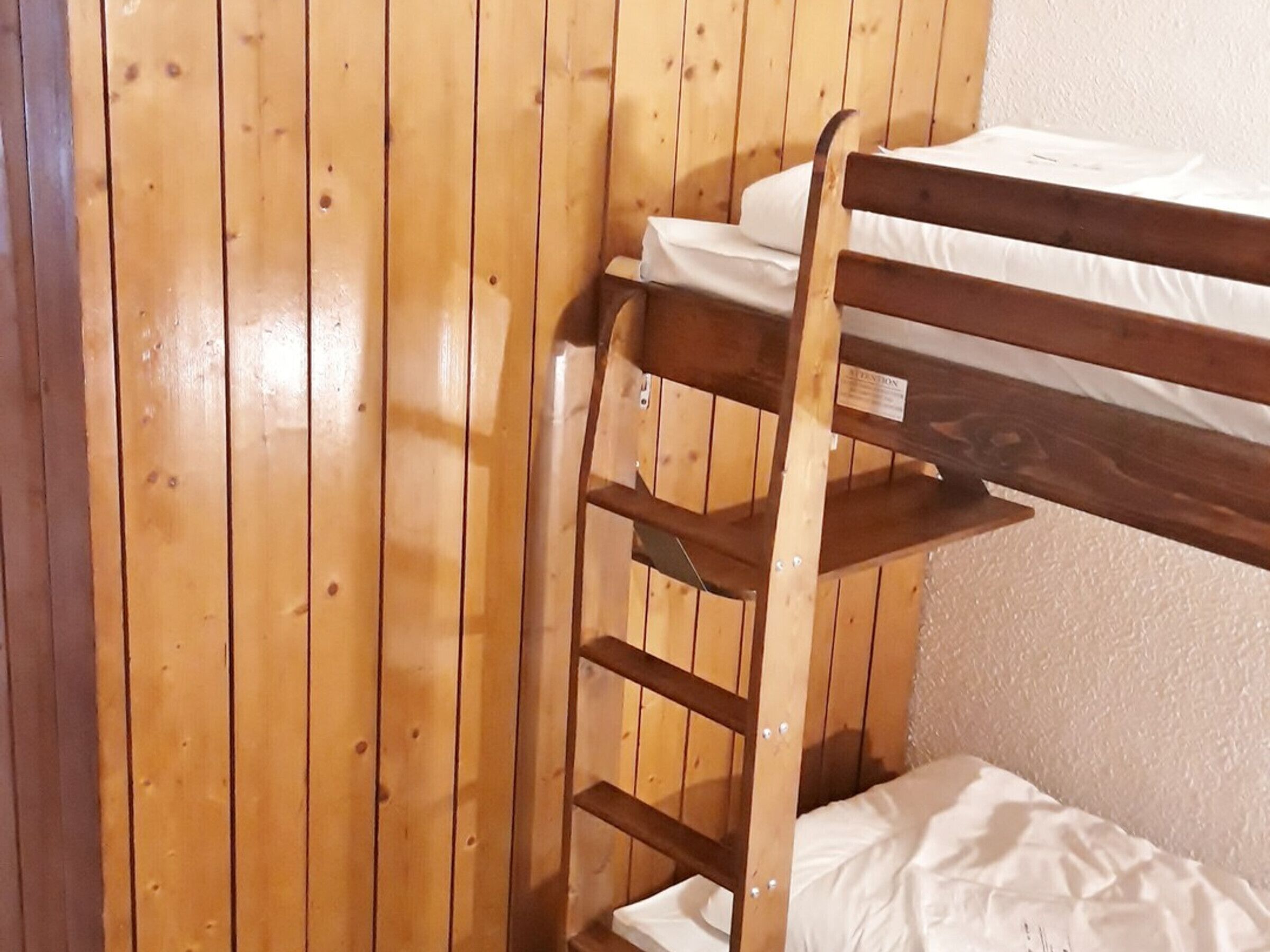 A bunk bed with a wooden ladder and a white mattress.