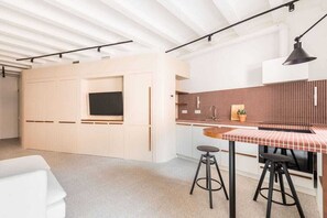 Una cocina moderna con salpicadero de baldosas rojas, un televisor de pantalla plana y una zona de bar con taburetes.