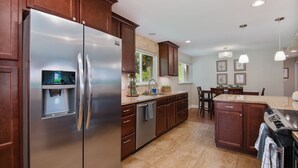 Una cocina moderna con electrodomésticos de acero inoxidable, armarios de madera y encimera de granito.