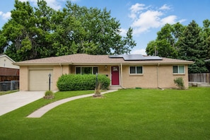 A single-story house with a red door, a garage, and a well-maintained lawn.