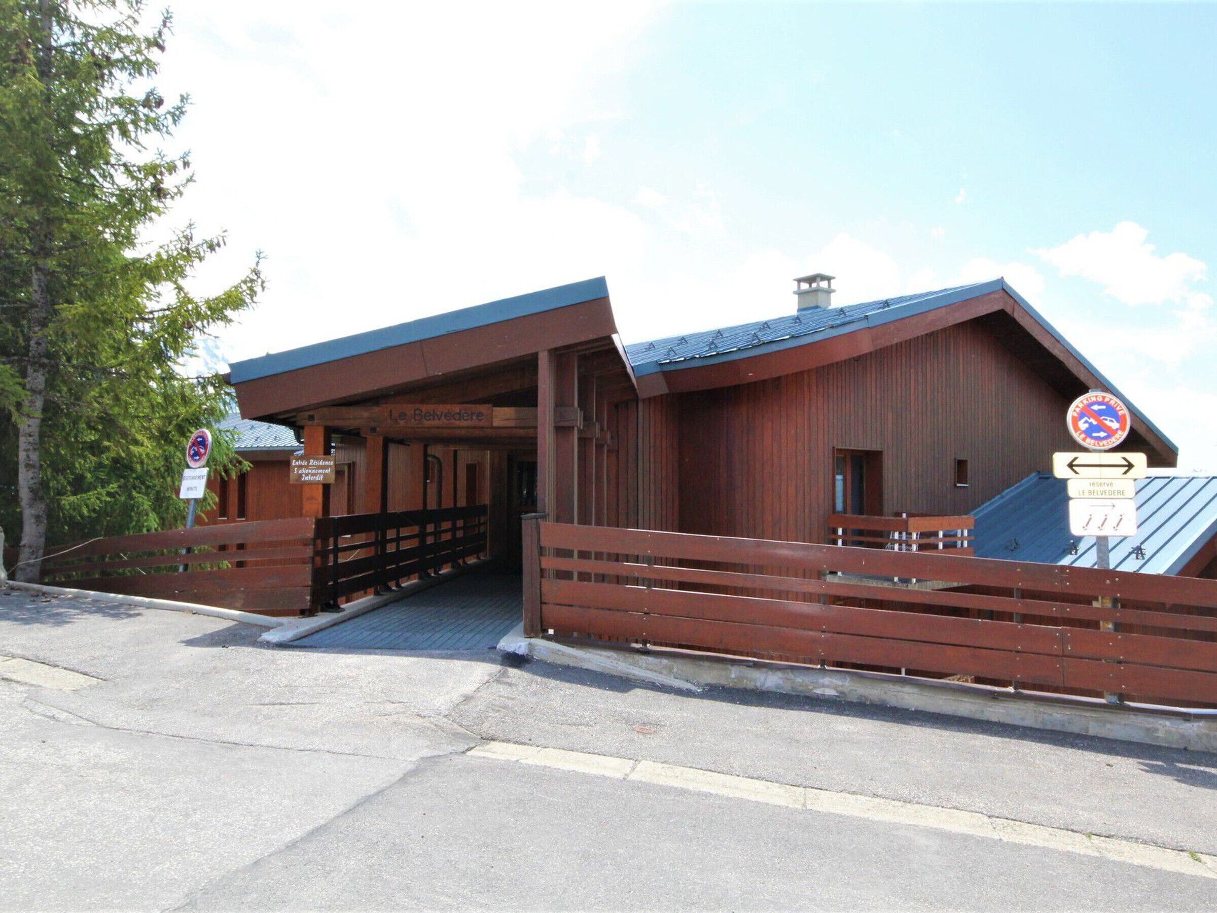 A wooden building with a sign reading "Le Belvédère" and a no parking sign.