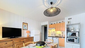 Un espacio habitable compacto con comedor, cocina y televisor.