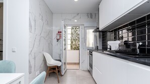 Een moderne keuken met witte kasten, zwarte aanrechtbladen en een marmeren spatwand.