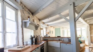 Une cuisine avec des murs en pierre, des poutres en bois, un évier et une fenêtre.