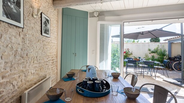 Un coin repas avec une table en bois, des chaises et un plateau bleu contenant des tasses.