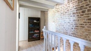 Un couloir avec un escalier en bois, un mur en pierre et un buffet en bois foncé.