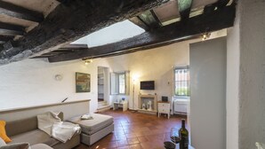 A cozy living room with a fireplace, a sofa, and a dining table with wine glasses. - [Trastevere] Cozy & Charme Apartment in Rome (Roma)