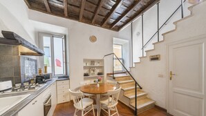 A kitchen with white cabinets, a round wooden table, and white chairs. There is a staircase with a sign indicating WiFi availability. - [Trastevere] Cozy & Charme Apartment in Rome (Roma)
