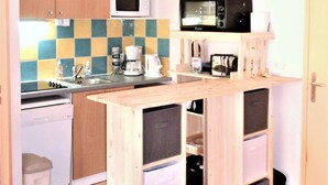 A compact kitchen with a microwave, coffee maker, and a small sink.