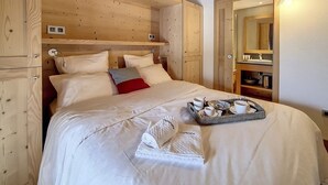 Une chambre à coucher de style cabane en bois, avec un lit, des oreillers, un plateau avec des tasses et une serviette.