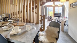 Une pièce chaleureuse avec un décor intérieur en bois, un coin repas avec une table et des chaises, un canapé et un téléviseur.