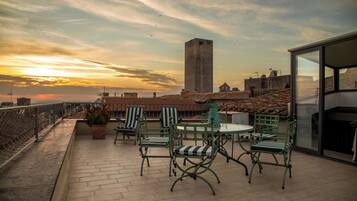 Une terrasse avec des sièges extérieurs, une vue sur le paysage urbain et un grand immeuble en arrière-plan.