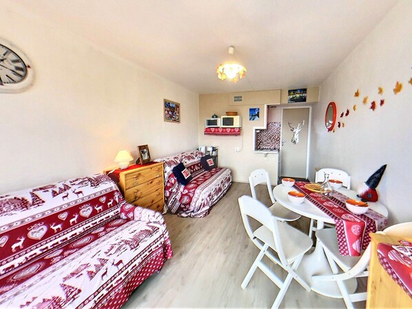 A cozy room with a sofa set, a wooden dresser, a dining table with chairs, and a wall clock. - Studio 3/4 pers, ski-in/ski-out, balcony, WIFI (Le Corbier)