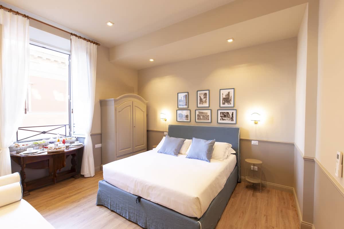 A neatly arranged bedroom with a bed, bedside table, and a small desk with a chair.