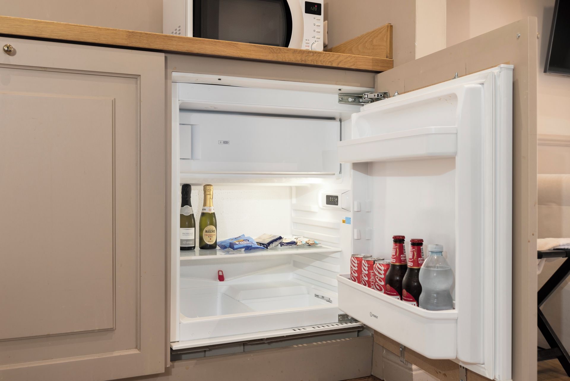 An open refrigerator with shelves containing bottles and cans.