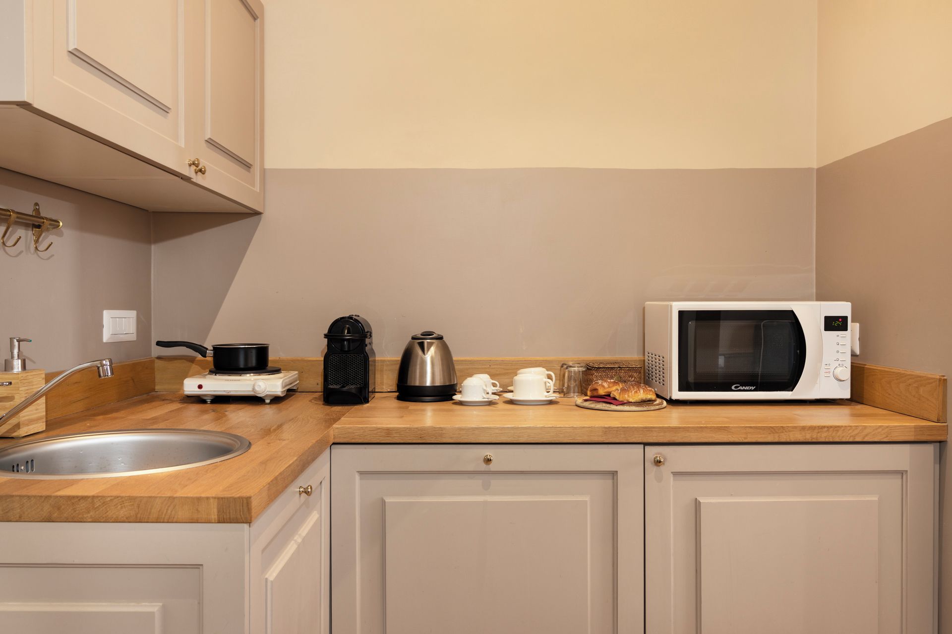 A kitchen with a microwave, coffee maker, and a pot on the counter.
