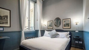 A neatly made bed with white linens, a bedside table with a lamp, and a framed picture on the wall. - Hotel Donna Francesca (Rome)
