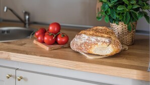 A kitchen counter with a loaf of bread, a basket of tomatoes, and a potted plant. - Hotel Donna Francesca (Rome)
