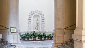 A marble staircase leading to a statue in an arched niche, surrounded by potted plants. - Hotel Donna Francesca (Rome)