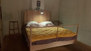 Ein hölzernes Bett mit Kopfteil, zwei Nachttischen und einer Nachttischlampe.