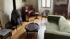 Ein Wohnzimmer mit Klavier, einer Couch, einem Tisch und einem Kamin.