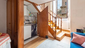 Een ruime kamer met een keuken, een trap en uitzicht op buiten.
