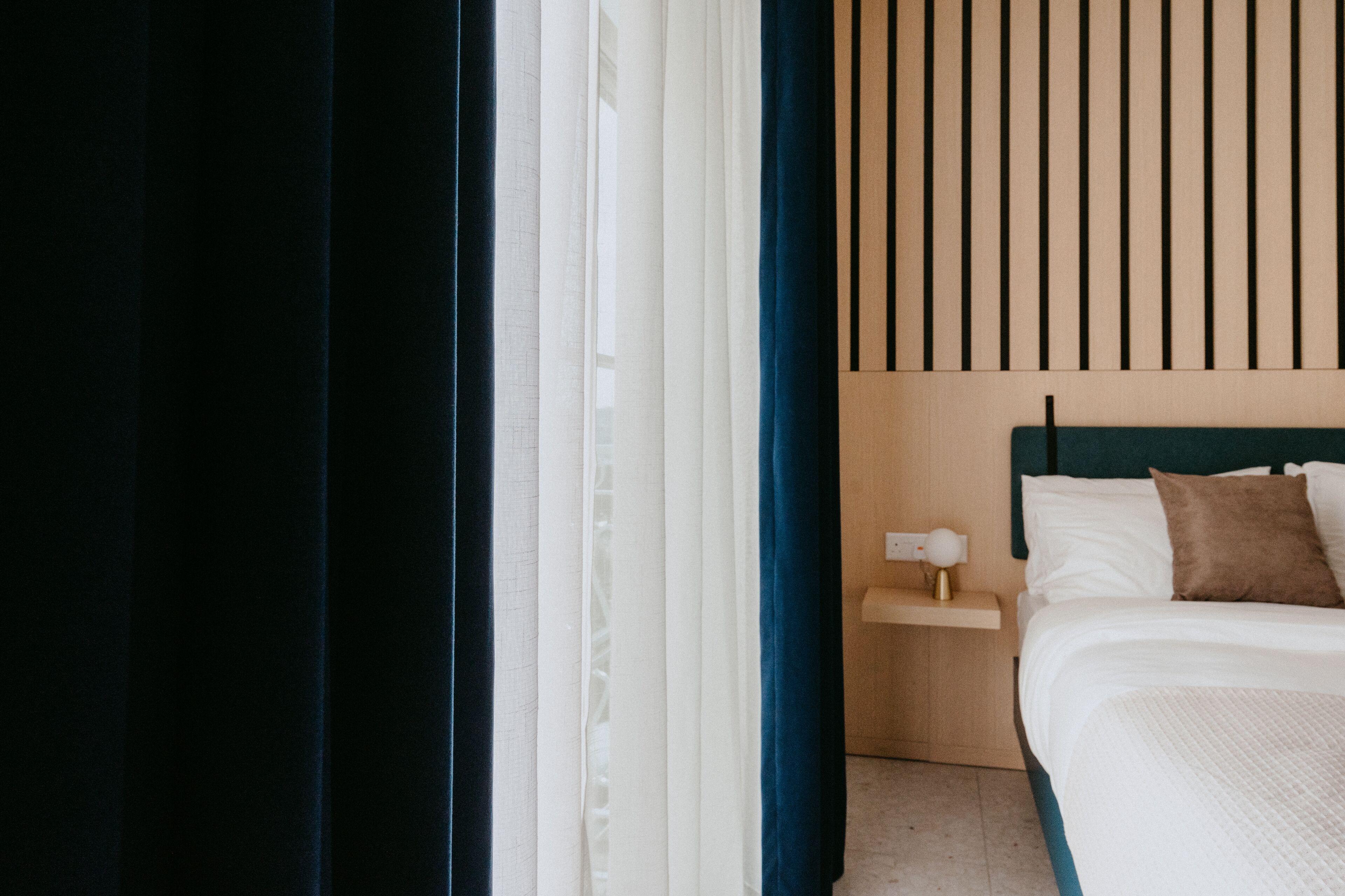 Una habitación de hotel con una cama, una mesita de noche y una ventana con cortinas.