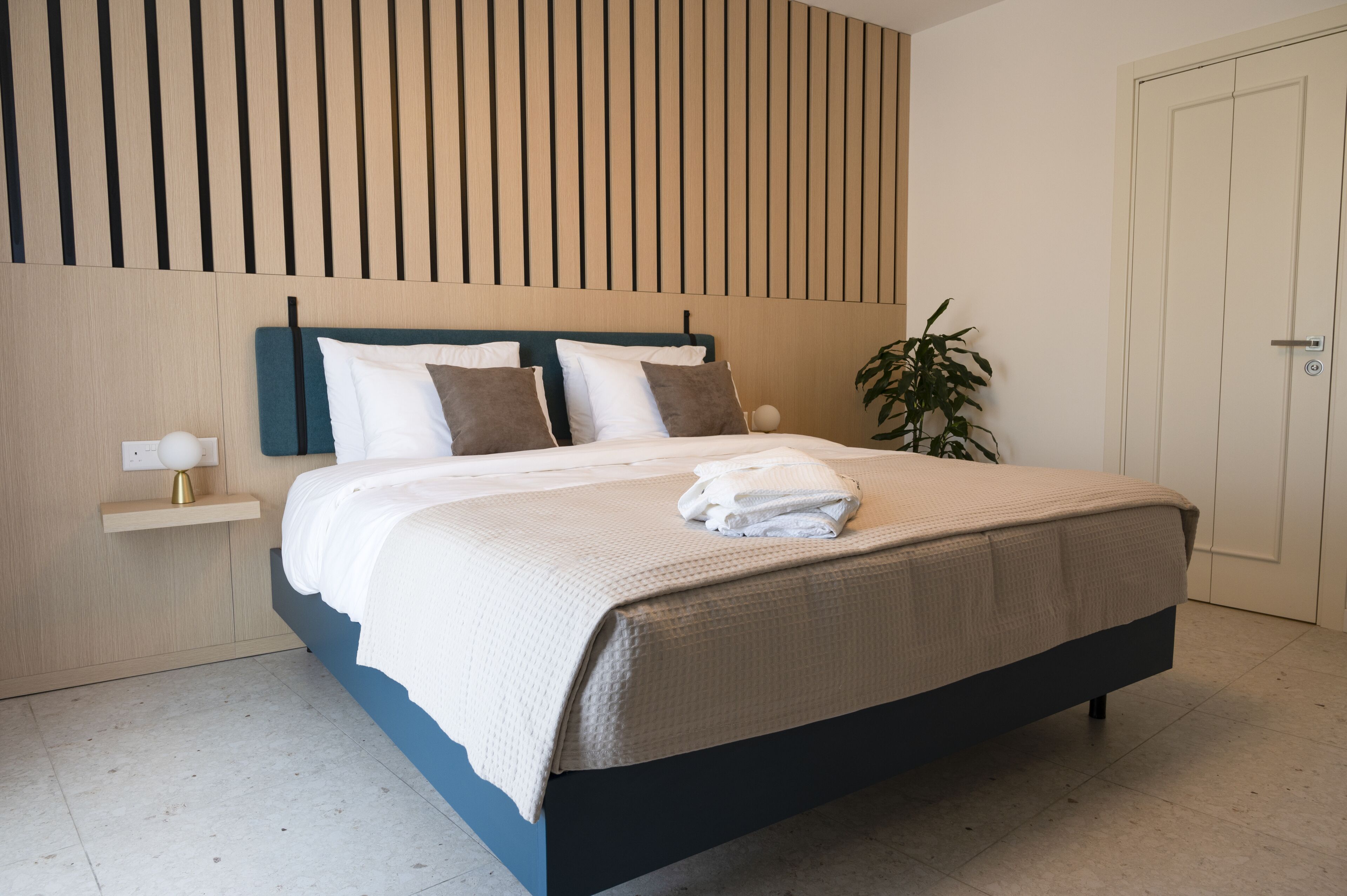 Un dormitorio moderno con cama, mesita de noche y panel en la pared.