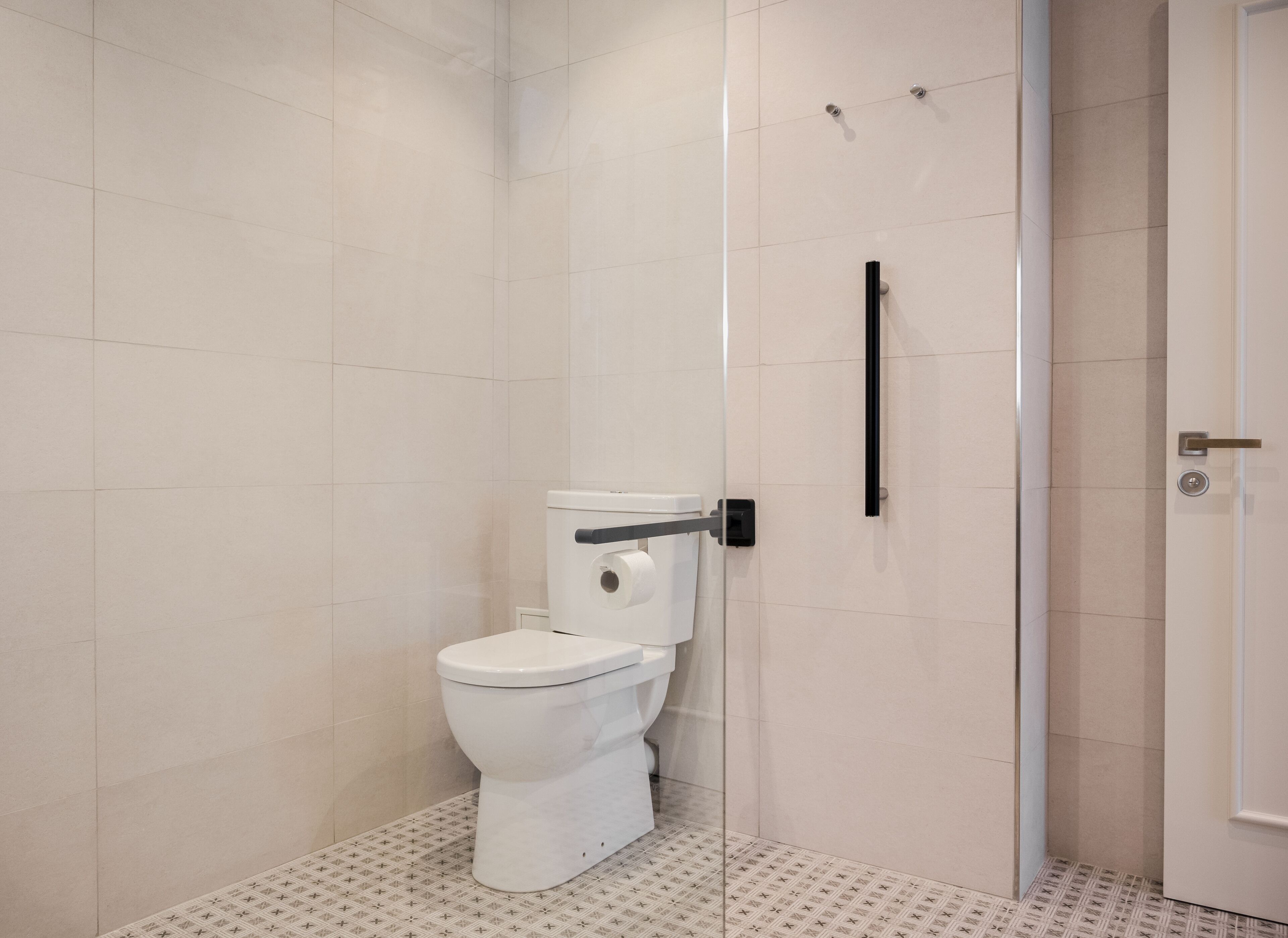 Une salle de bain moderne équipée de toilettes, d’une douche et d’une porte.