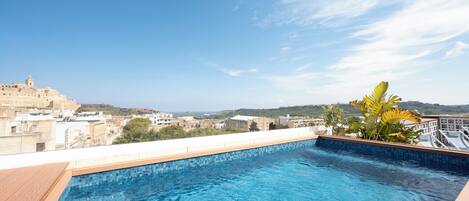 A rooftop pool with a clear view of the cityscape and distant hills.