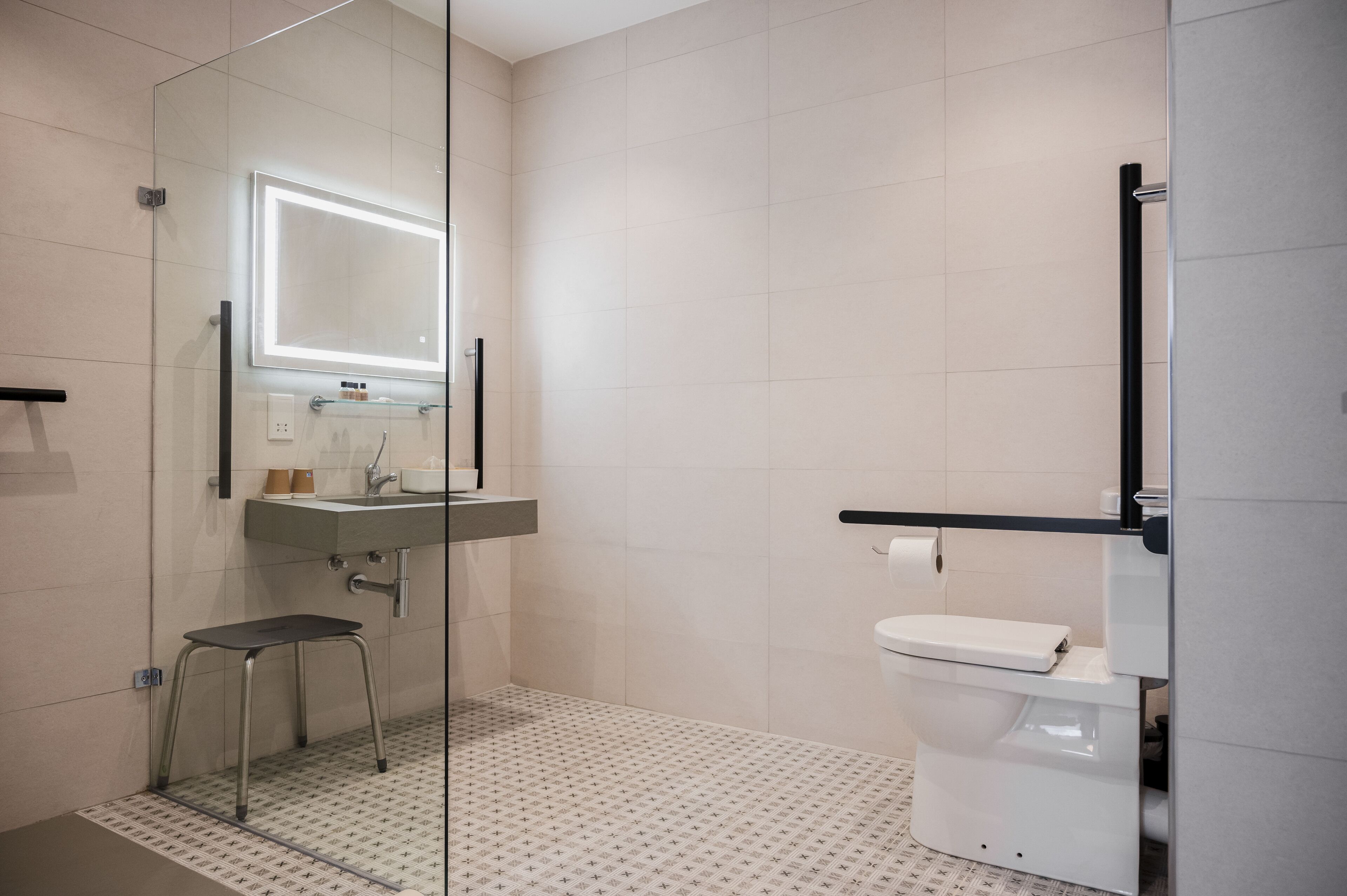 A modern bathroom with a glass shower enclosure, a toilet, and a sink with a mirror above it.