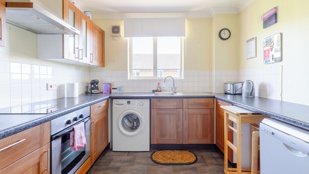 A compact kitchen with a washing machine, a dishwasher, and a sink. - Homely 1 Bedroom Apartment in Beckton With Parking (London)