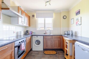 A compact kitchen with a washing machine, a dishwasher, and a sink. - Homely 1 Bedroom Apartment in Beckton With Parking (London)