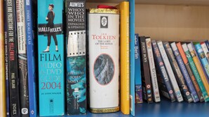 A bookshelf with various books, including titles like 'The Lord of the Rings' and 'Film Video & DVD Guide 2004'. - Homely 1 Bedroom Apartment in Beckton With Parking (London)
