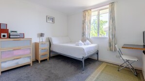 A bedroom with a bed, a desk, a chair, a dresser, and a window with curtains. - Homely 1 Bedroom Apartment in Beckton With Parking (London)